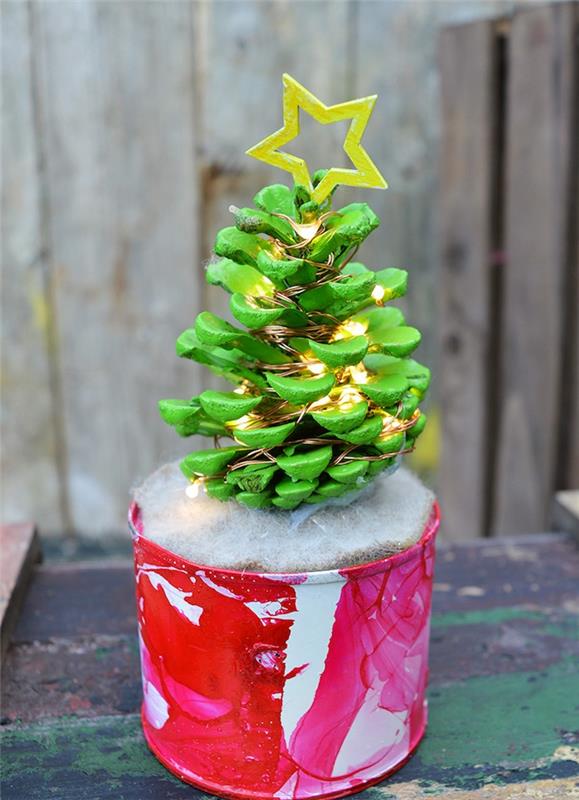 Vianočná dekorácia, ktorá si urobíte s rekuperáciou, šiška premaľovaná zelenou farbou so svetlou girlandou a žltou drevenou hviezdou