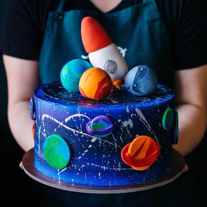 modelová narodeninová torta s modrofialovou polevou a figúrkami z cukrovej pasty napodobňujúcich planéty slnečnej sústavy