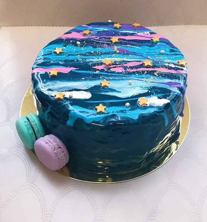 zrkadlová poleva na zriedenú modrú, ružovú a bielu efektnú narodeninovú tortu a zelenú a purpurovú dekoráciu makrónok