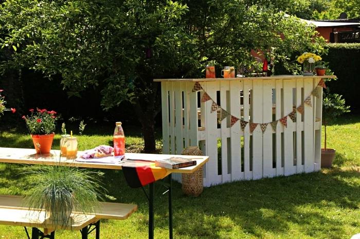 träpallskåp för trädgården eller terrassen, pallträdgårdsbar dekorerad med en vimpelkrans installerad bredvid trädgårdsmöblerna