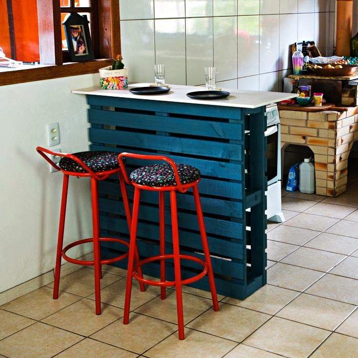 en köksstång i återvunnen pall ommålad i ankblå, återvunnen pallköö med två röda barstolar i metall