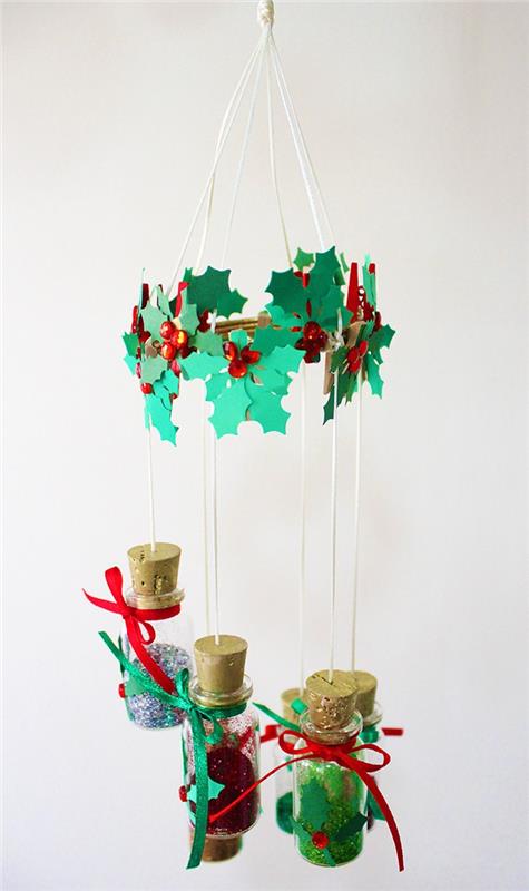 Vianočný mobil na zavesenie zo stropu v liekovkách naplnených trblietkami a korunou z kamienkov a lístkov z cesmínového imitačného papiera