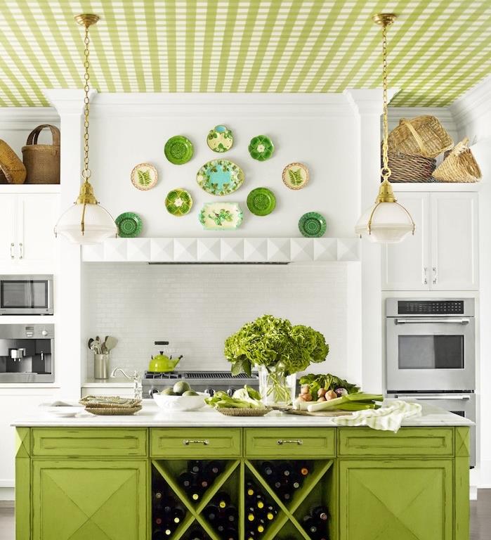مطبخ ريفي أنيق مع خزانة أمامية بيضاء ، وأجهزة مدمجة من الفولاذ المقاوم للصدأ ، وجزيرة مركزية خضراء ، وأواني فخارية مزخرفة وسقف أخضر ، وسلال زخرفية