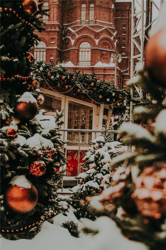aká tapeta na vianoce, obrázok Veselé Vianoce 2019 s tehlovou fasádnou budovou a veľkými ozdobenými jedľami