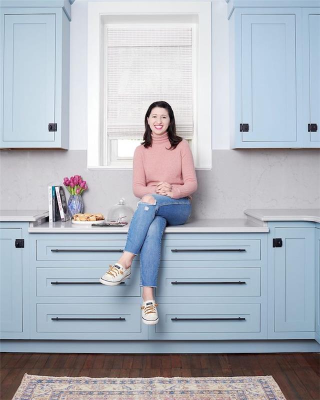 Žena sediaca na kuchynskej farbe, ktorá spolu ladí, trend v domácom zdobení svetlo modrá kuchynská farba