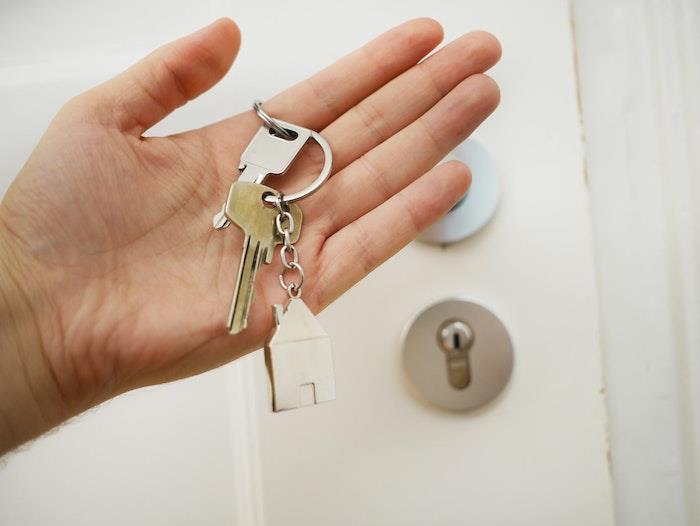 kvinna som håller nycklarna till hennes lägenhet vit ytterdörr