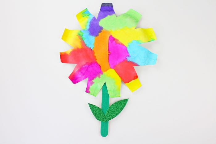 farebný kvet na výrobu seba a papiera farby akvarel a stonka v tyčinke zmrzliny a trblietavé zelené listy