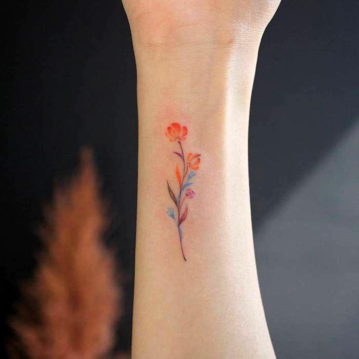 idé om liten blomma i färg med löv och blommor i olika färger, minimalistisk tatuering modell kvinna