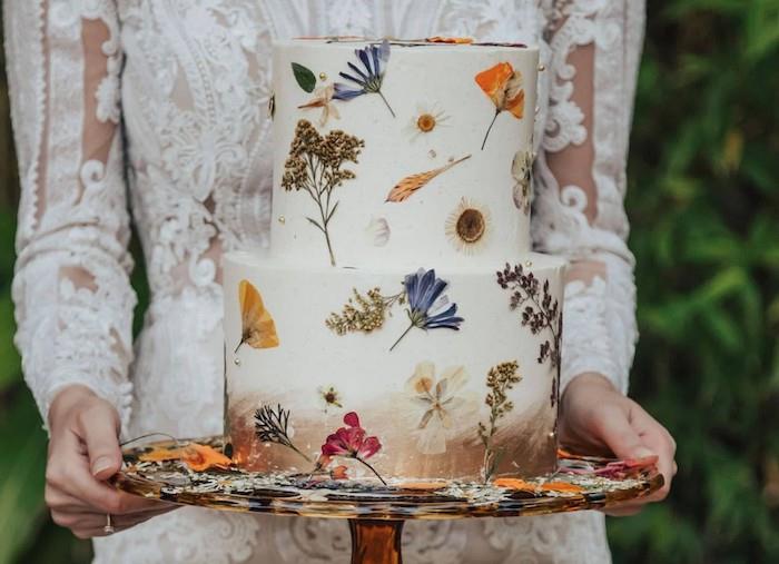 ätbara pressade blommor för att dekorera en original bröllopstårta i vit och brun bas