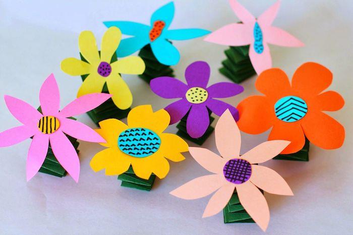 kvet v stonke papiera zložený v harmonike a kvet z farebného papiera so stredom v kruhu farebného papiera s rôznymi vzormi