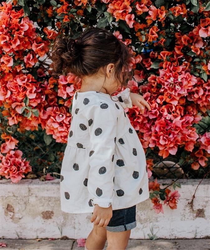 Rozkošné dievčatko hrajúce sa s kvetmi na ulici, strih malého dievčatka, ľahký účes na úpravu vlasov pre malé dievčatká