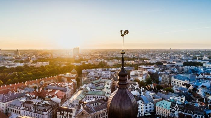 toppen av en kyrka med en bronshane, europeisk stad, klarblå himmel utan moln, sommarstämning, stigande sol