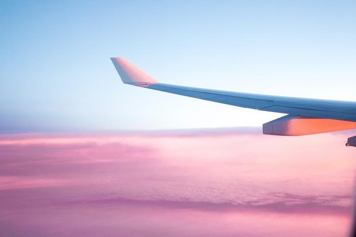 صورة رحلة الطائرة مع السماء الزرقاء والغيوم الوردية ، خلفية جميلة لخلفية الكمبيوتر على موضوع السفر