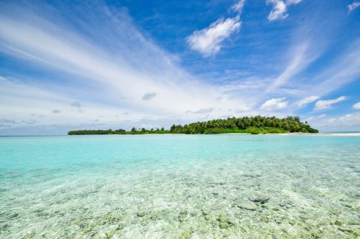 en ö i Indiska oceanen, paradisiskt landskap i grön och turkos färg, himlen strålar av solsken med moln som ser ut som känsliga gardiner