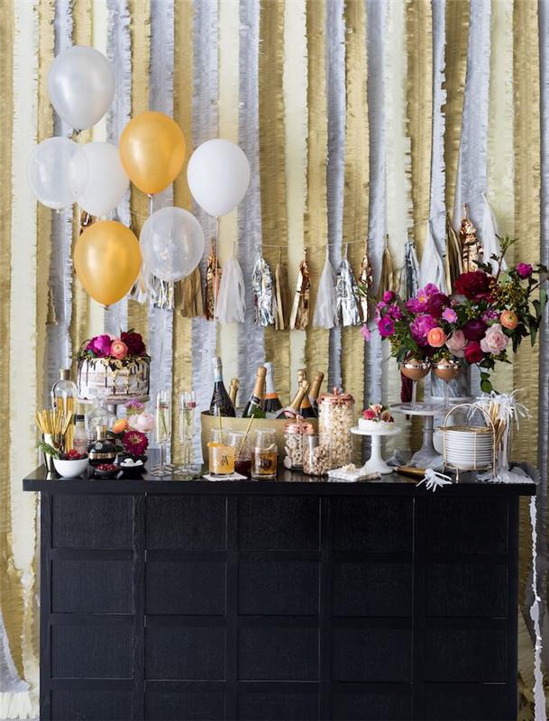 nyårs godisbar med glasögon, champagneflaskor, bukett blommor och nyårstårta, devoballong och kransar i bakgrunden