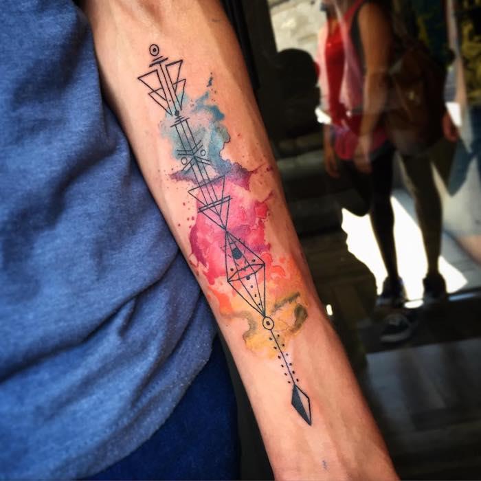 Tatuaggio uomo braccio con forme geometriche e uno sfondo colorato