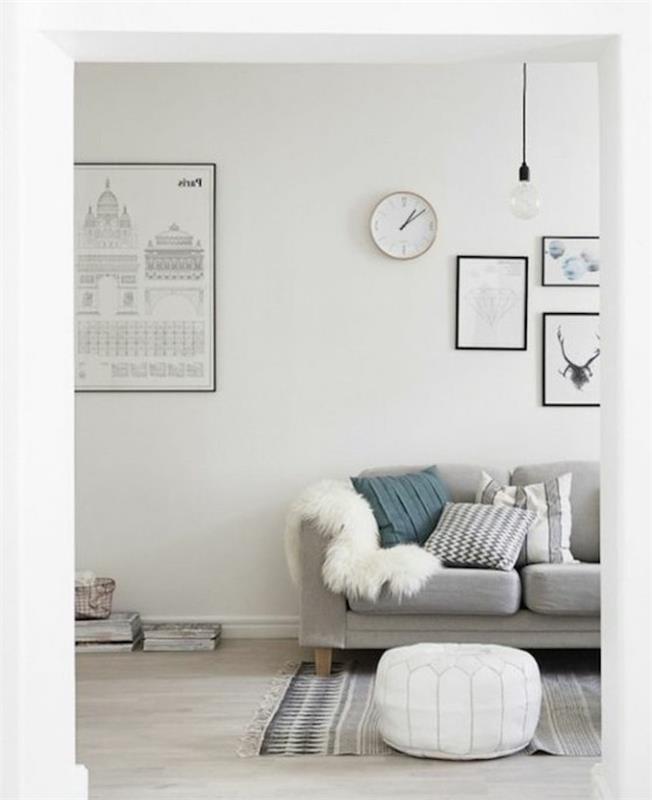 vit ottoman, grå soffa, ljusgrå väggar, inramad hängande konst, blå kudde, gul furig filt