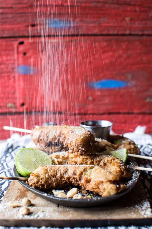 stekta bananer, grönsaks aptitretare, skivad lime, täckt med pudersocker, på en träskiva