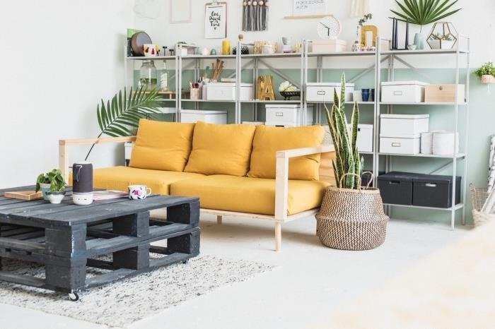 stará garáž premenená na bohémsky loft zariadený nábytkom vyrobeným na mieru, originálny konferenčný stolík s dvoma skladanými paletami v kontraste so sedačkou pre domácich majstrov v drevených doskách