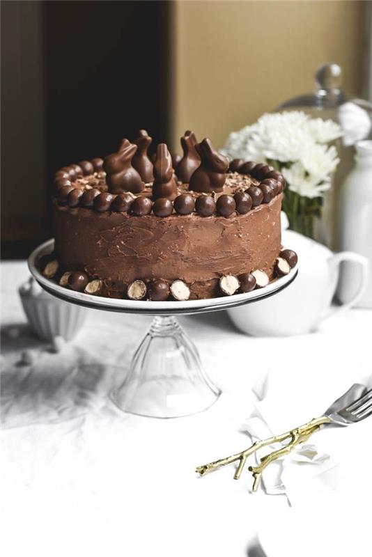 enkel och utsökt choklad påsktårta, mjuk tårta täckt med smörkräm och chokladglasyr, med dekoration av påsktema med små chokladkaniner