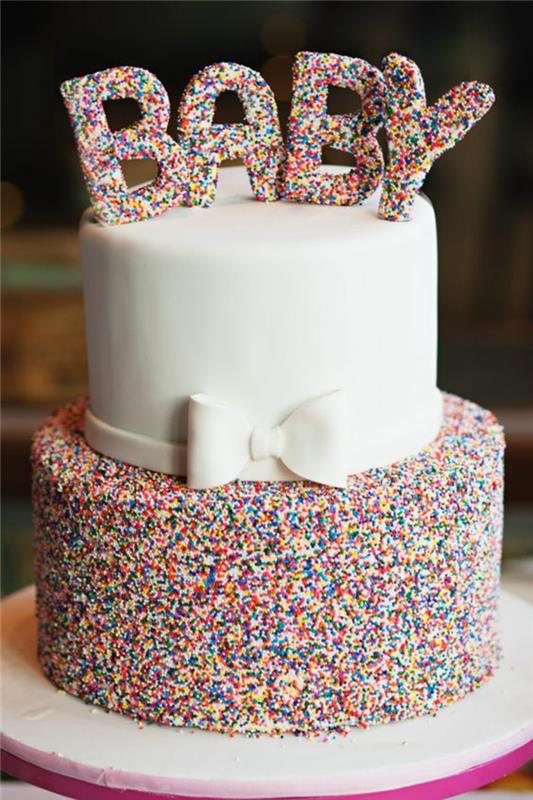 en söt baby shower -tårta dekorerad med regnbågsstänk, en hantverksmässig baby shower -tårta