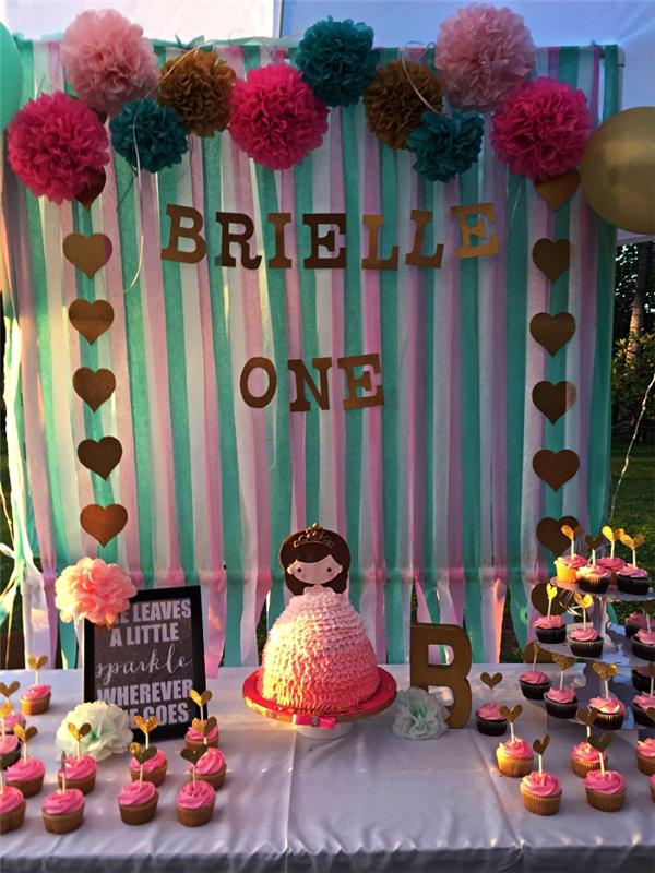 gourmetbuffé på prinsessans födelsedagstema med dekoration av mjukpappersbollar och fransad gardin som bakgrund