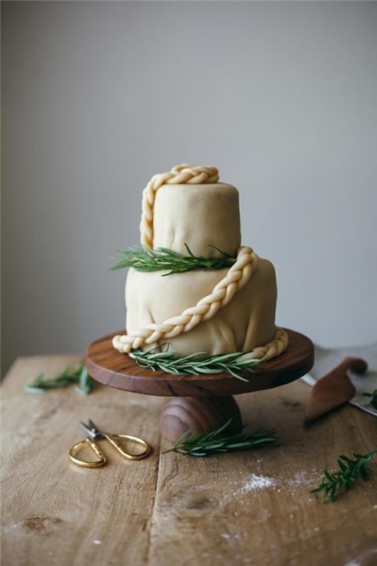 super elegantná biela svadobná torta, drevený stôl, nožnice so zlatými rúčkami, ozdoba z borovicových vetvičiek
