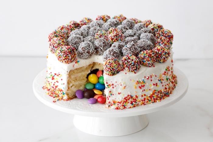 Mjuk vaniljkaka fylld med smarties med smörglasyr, dekorerad med choklad och kokosbollar
