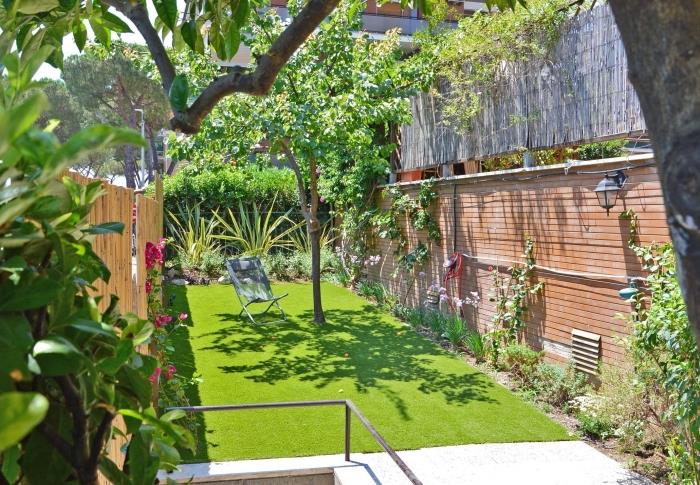 فكرة تنسيق الحدائق مع سياج خشبي ، فناء خلفي صغير مع العشب الاصطناعي والزواحف
