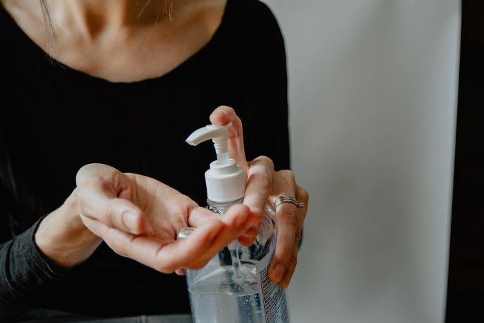 Disinfettante per le mani fatto in casa، donna che si versa il disinfettante sul palmo della mano، amuchina fatta in casa