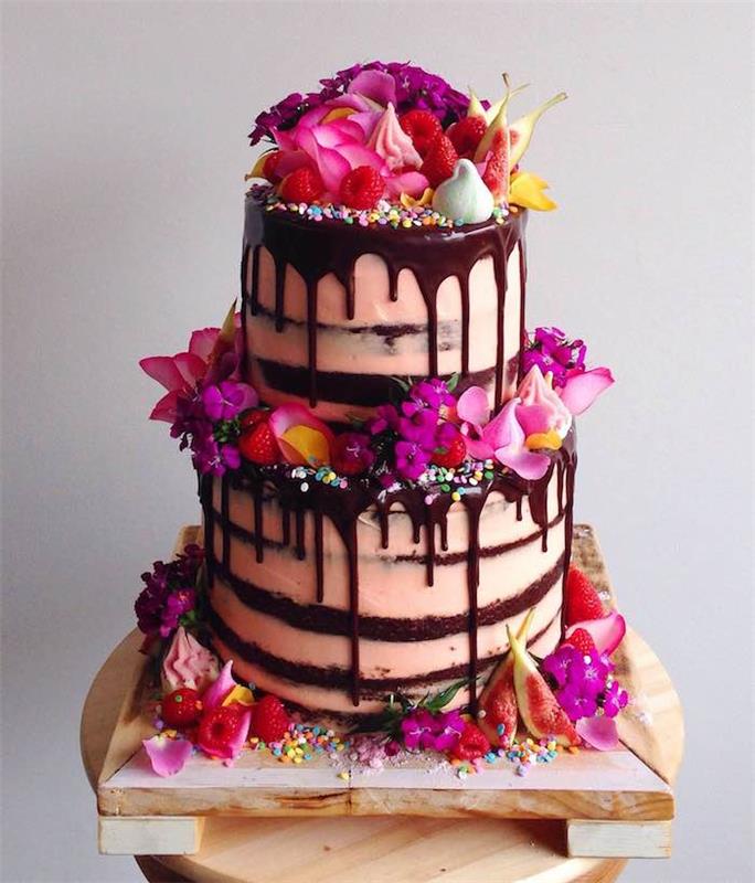 chokladglasyr för att dekorera en födelsedagschokladkaka med rosa grädde, dekoration av färska blommor, färgade marmor, maränger och frukter