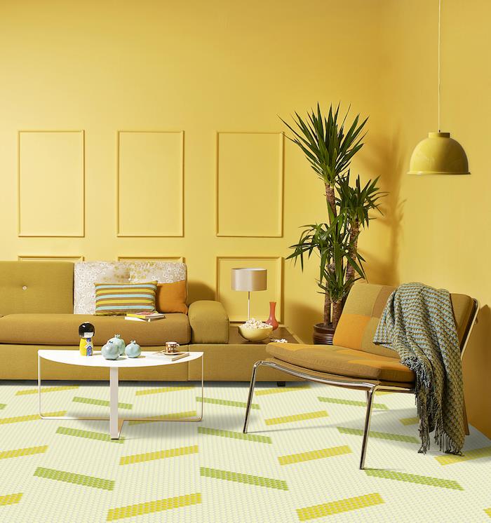 žltá výzdoba obývačky s horčicovo žltou sedačkou a žltou stoličkou, biely minimalistický stôl, vnútorná palma v kvetináči