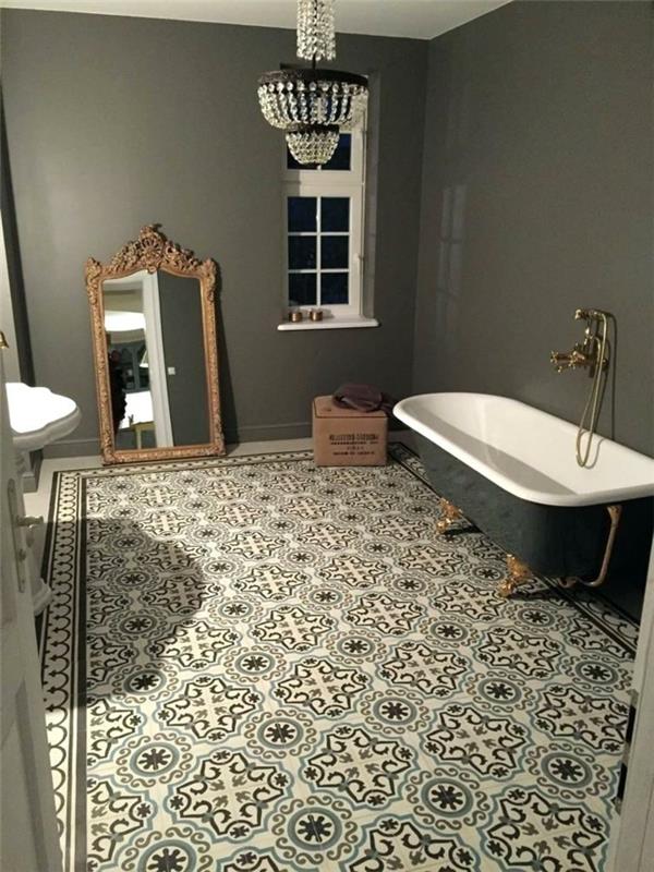 cementplattor på badrumsgolvet i grått och vitt, spegel med barockram, badkar i gjutjärn och väggkran, orientalisk taklampa