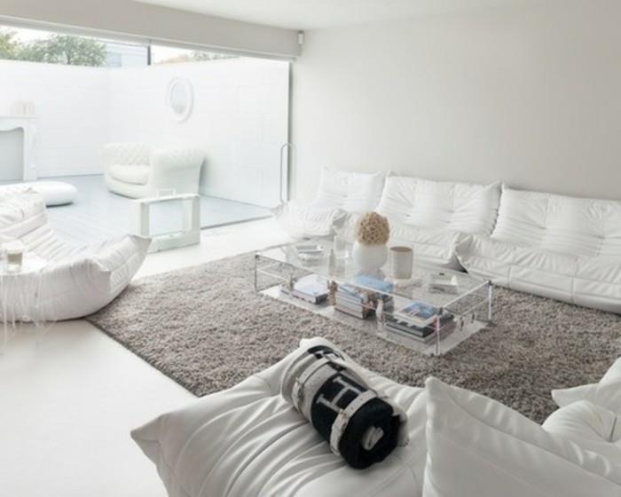 vita soffor och fåtölj, soffbord i glas, grå färgscheman, stor grå matta, stort fönster
