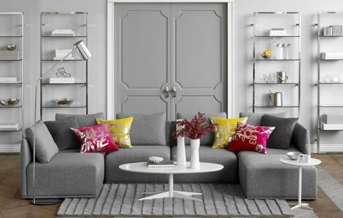 grå vardagsrumsväggar, grå hörnsoffa, rosa och gult, kuddar, grå matta, vitt soffbord