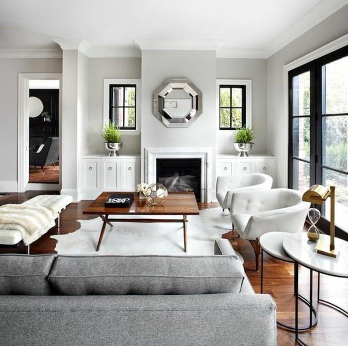 vita fåtöljer, spegel ovanför spisen, accentfärger för grå, grå soffa, soffbord i trä