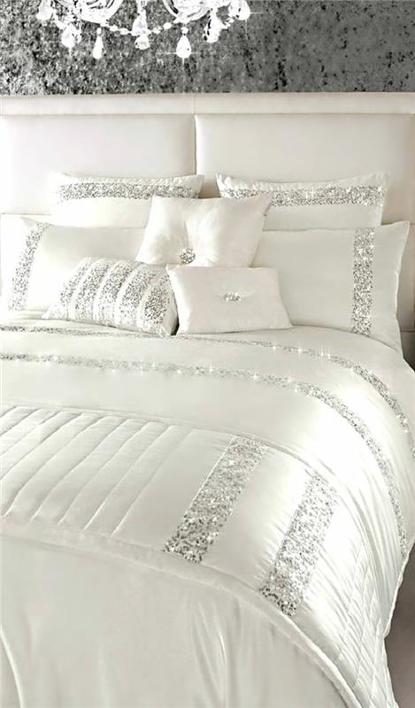 perleťovo šedá lakovaná posteľ v bielej farbe s ozdobnými pruhmi v trblietavej šedej s veľkým lesklým lustrom