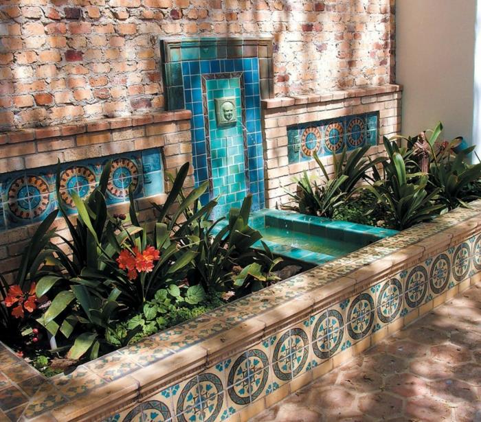 vonkajšie obklady stien, záhradná fontána s mužskou hlavou a vodou vychádzajúcou z jeho úst, mozaika v tyrkysovo modrej a jazernej zeleni, stena v červených biruqoch