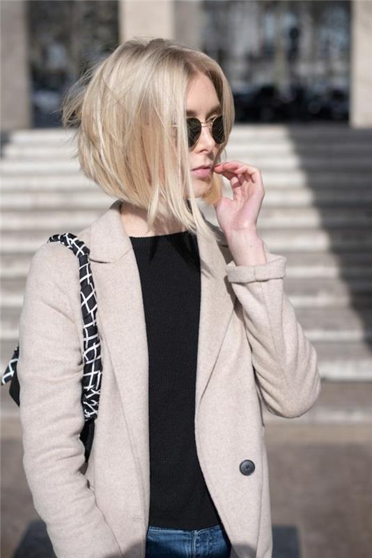 účesy pre krátke vlasy, žena s krátkym blond bobom a čiernymi okrúhlymi slnečnými okuliarmi, na sebe čierny top a svetlo krémový blejzer