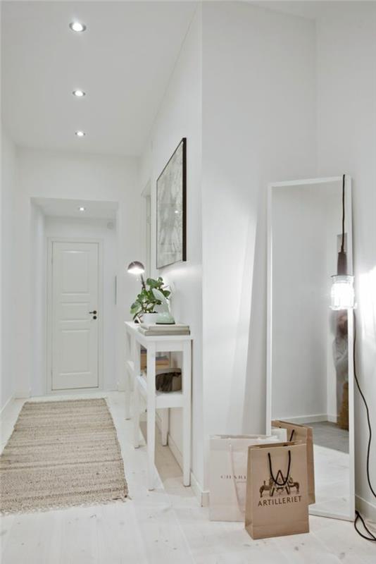 vybavte vstupnú halu celú v bielom s veľkým zrkadlom opretým o stenu osvetlenou veľkou dizajnovou žiarovkou