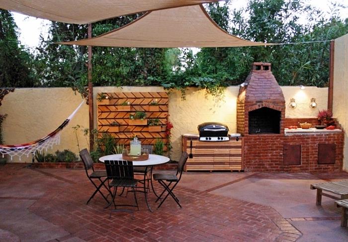 trädgård dekoration med hängande hängmatta och hörn av litet kök utrustat med grill i röda tegelstenar