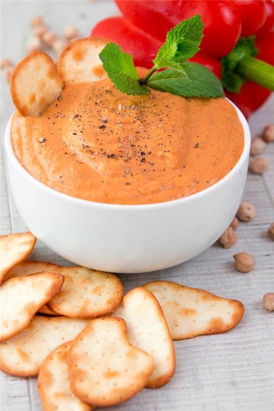 hummus i en vit skål, enkla veganska aptitretare, bakade kex på sidan
