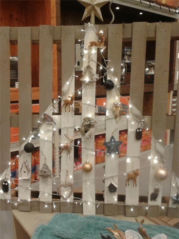 Vianočný stromček namaľovaný na palete, ozdoba vianočného stromčeka, biele svetlá veniec, jelene, jedle a hviezdy, sovy a zlaté a strieborné gule