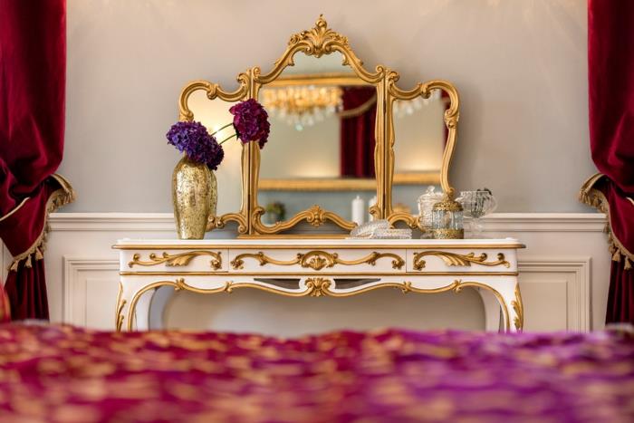boudoir sovrum, sminkhörna, gyllene spegel, långa röda gardiner, vita väggar, gyllene vas, lila blommor