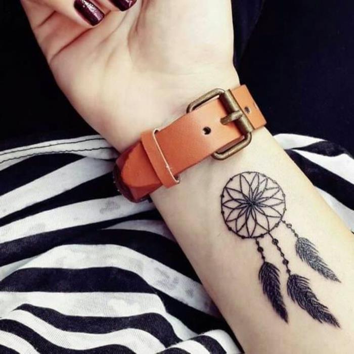 Dreamcatcher tatuering underarm grafik, svart bläck, rosett, fjädrar, pärlor, en brun klocka, hur man får en tatueringsidé för en kvinna