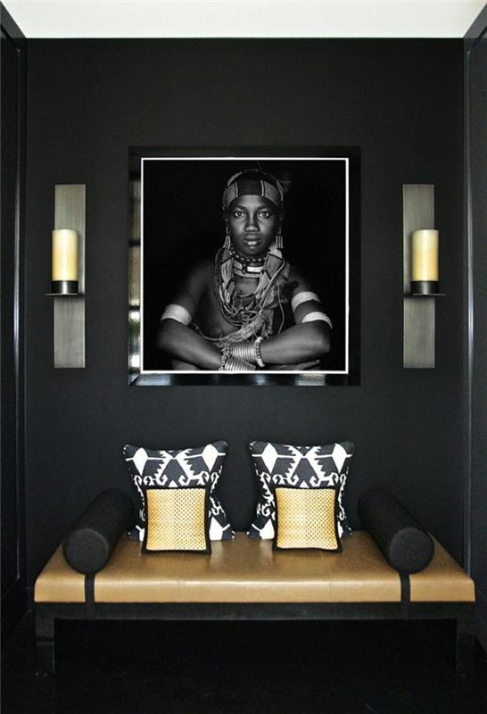 أضواء حائط بالقرب من صورة لصبي بري ، ديكور بألوان ترابية ، مقعد على مقعد باللونين الأسود والبيج