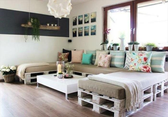 Mobili con palet, divano angolare decorato con cuscini colorati e un tavolino basso