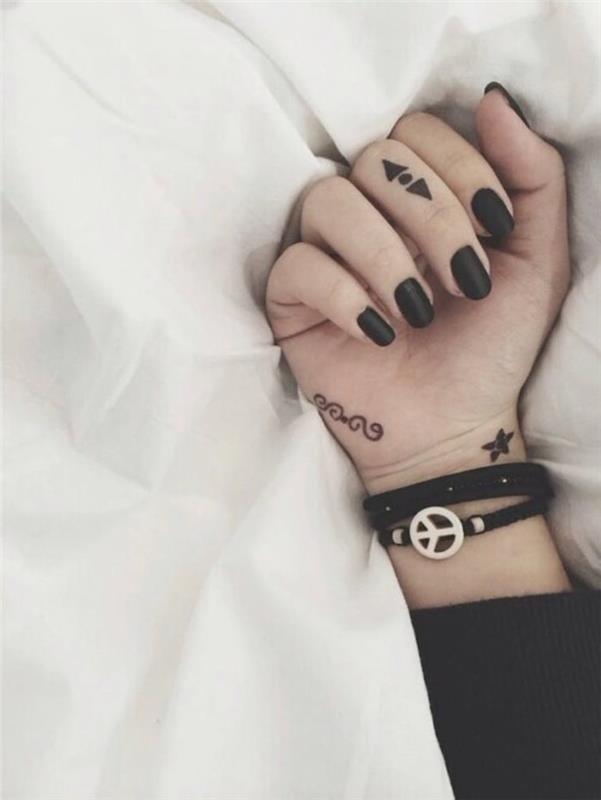 Donna con la mano tatuata con simboli e inchiostro di colore nero