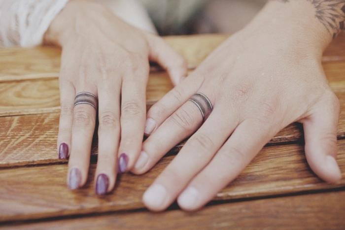 Tatuaggio sulle dita di un uomo e una donna con gli anelli da fidanzamento