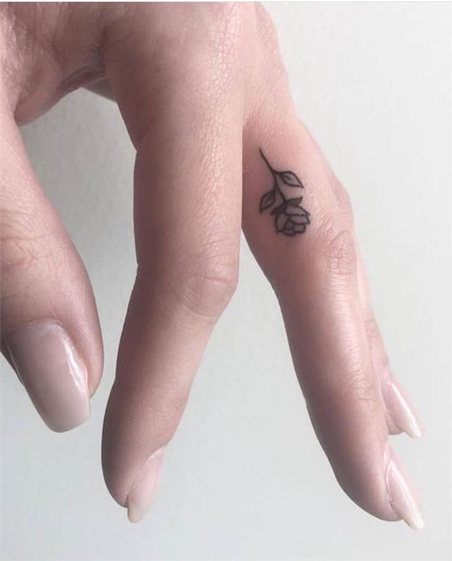 Tatuaggio sul dito medio di una donna con il disegno di una piccola rosa